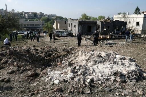 People gather at the site of a rocket strike in Zarzir, northern Israel
