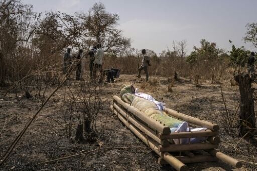 A victim's body rests on a wooden stretcher after a massacre in the Nigerian village of Woro