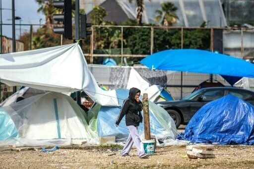 A displaced girl walks past tents covered in plastic sheeting to shield them from the stormy weather along Beirut’s seafront area
