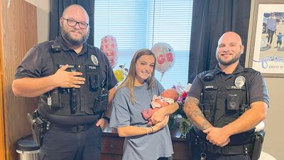 From left are Cpl. Jacob Schurman, Kylie Christopher holding Willow Dobbs, and Patrolman Craig Burch.