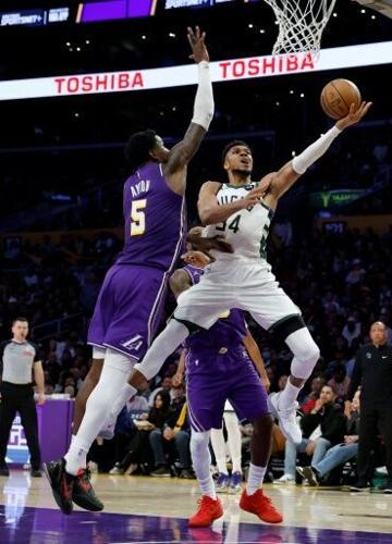 Milwaukee's Giannis Antetokounmpo scores on a layup in front of Deandre Ayton in the Bucks' NBA victory over the Los Angeles Lakers