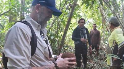 Daniel Pierce observes a Brazilian nut with a guide, Hertizog Nascimento, and local villagers.