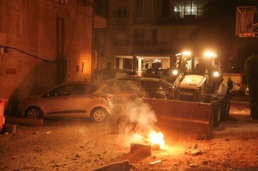 Israeli security works to put out a fire caused by a rocket strike in Holon, Israel