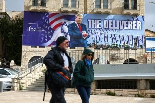 People walk past a banner in Jerusalem depicting US President Donald Trump with the slogan 'The Deliverer' in Jerusalem
