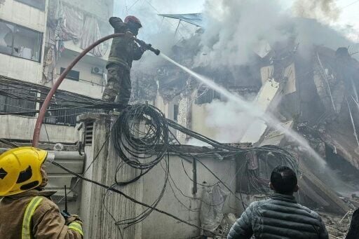Firefighters at a site of an Israeli air strike in Beirut’s southern suburbs