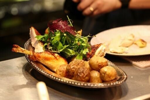 A cook prepares a rotisserie chicken with potatoes during dinner in the French restaurant Gigi’s in the Brooklyn borough of New York City on April 26, 2026