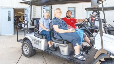 Angie Price, left, and Gern Varner received a ride from Josh Meyer of the STL Golf Cart Shuttle Service, which provided transportation to and from the parking lot.