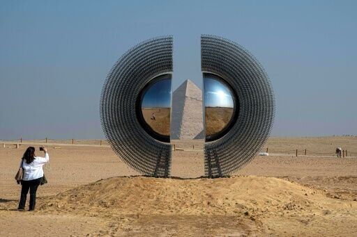 A woman takes a picture of the art installation "The Shen" by artist by Mert Ege Kose during the fifth edition of the "Forever is Now" art exhibition by Art d’Egypte at the Giza pyramids necropolis