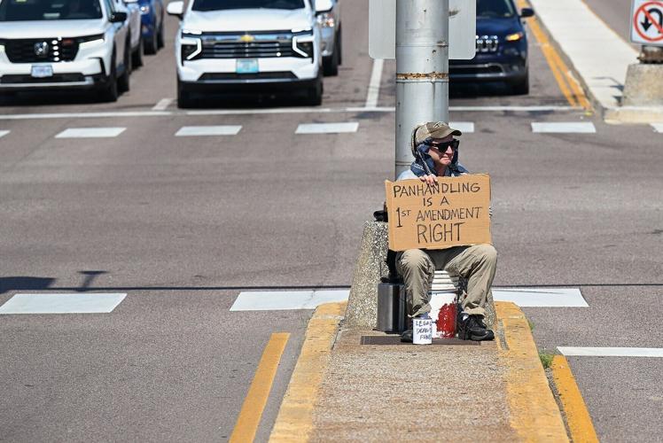 Dirk Burhans sits in the median waving as cars drive by
