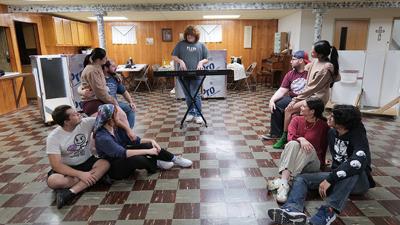 The cast practices a scene during rehearsal.