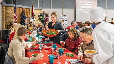 Recipe contest finalist Melissa Mantl of Hillsboro serves her Roasted Beet and Kale Salad to a table of guests at the Leader Holiday Dinner while the Jefferson College Jazz Combo performs in the background.