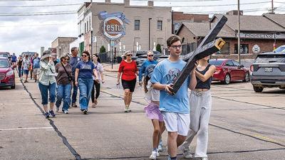 Timmy Bowen, 16, Rosalie Kerr, 7, and her sister, Kennedy, 11, carry the cross down Main Street in the 2026 Twin City Ministerial Alliance Good Friday Processional.