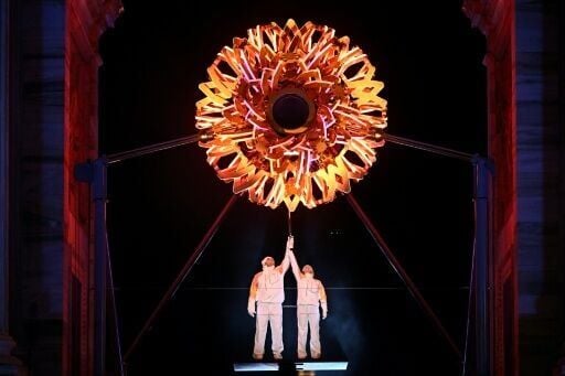 Italian skiing greats Alberto Tomba (L) and Deborah Compagnoni (R) light the Winter Olympics cauldron at the Arch of Peace in Milan