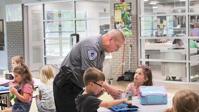 Rockwood Safety Officer Joseph Early helps a Eureka Elementary School student open her juice box during lunch.