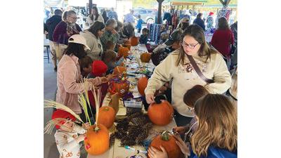 Visitors decorate pumpkins at the Arnold Farmers Market, which will be open from 8 a.m. to noon every Saturday through Nov. 8.