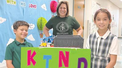 St. Joseph Catholic School students Reid Mattingly and Olivia Sanchez, front, with third-grade teacher Cathy Walsh with the Kind Kart.