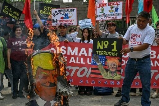 Protesters hold up a sign and burn an image of US President Donald Trump during a protest against the joint US-Philippine military exercises