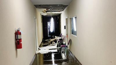 At 109 E. Main St., damaged and fallen ceiling tiles lie in floodwater in the hallway leading to the Dance Plus studio portion of the building.
