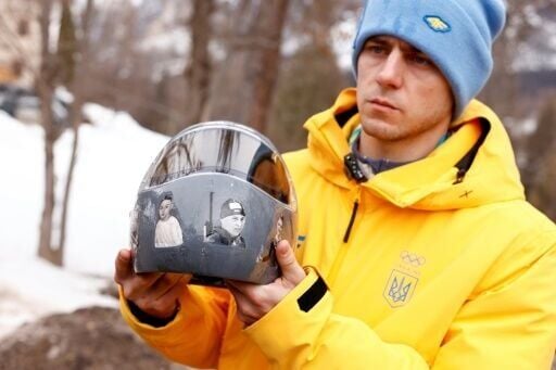 Ukrainian skeleton racer Vladyslav Heraskevych holds his helmet, which depicts victims of his country's war with Russia