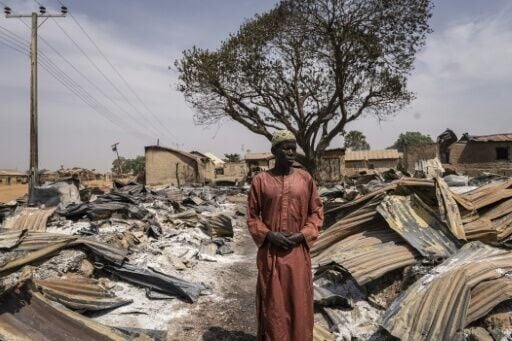 A resident surveys the charred remains of a neighbourhood in a Nigerian village attacked in a gruesome massacre