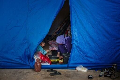 A woman cooks inside a tent at a stadium in Beirut converted into a shelter for people displaced by the conflict