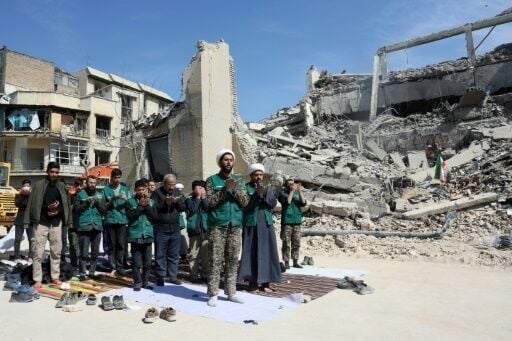 Iranian clerics and volunteers from the Bsij military who are helping clear the streets pray next to the rubble of a police station destroyed in airstrikes in central Tehran, on March 4, 2026.