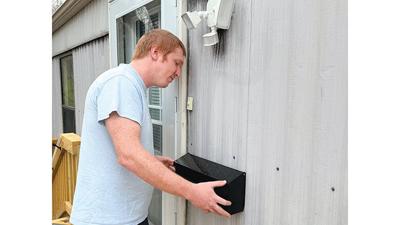 Andrew Swallow, a certified Aging-in-Place investigator at JFCAC, inspects a mailbox that was attached to a Festus home so the older residents can safely collect their mail. The front deck, which was rotting, was replaced using federal funding.