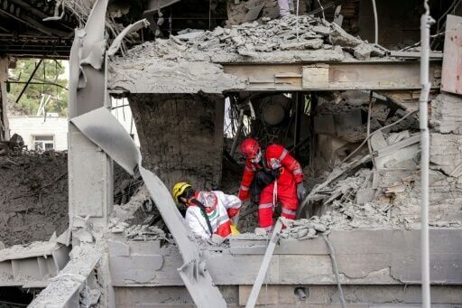 First responders search an office building that housed the offices of the Doha-headquartered news network Al Araby TV following a missile strike in Tehran