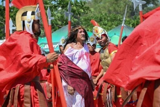 Ruben Enage (C) walks past actors wearing costumes of Roman centurions prior to his crucifixion on Friday
