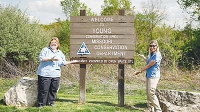Julie Stone, left, and Bonnie Harper show off the addition to the Young Conservation Area’s sign noting the role Open Space STL played in the expansion to the area.