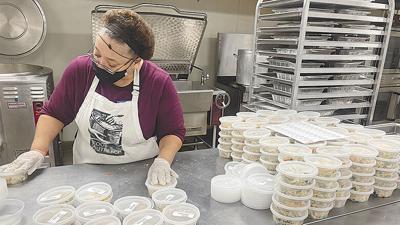 Volunteer Jeanette Carter packs containers of food in Food Outreach’s industrial kitchen.