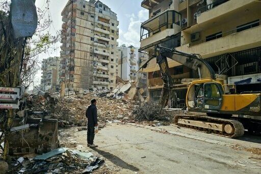 A bulldozer clears the rubble from the site of an Israeli airstrike as people return to Beirut's southern suburbs