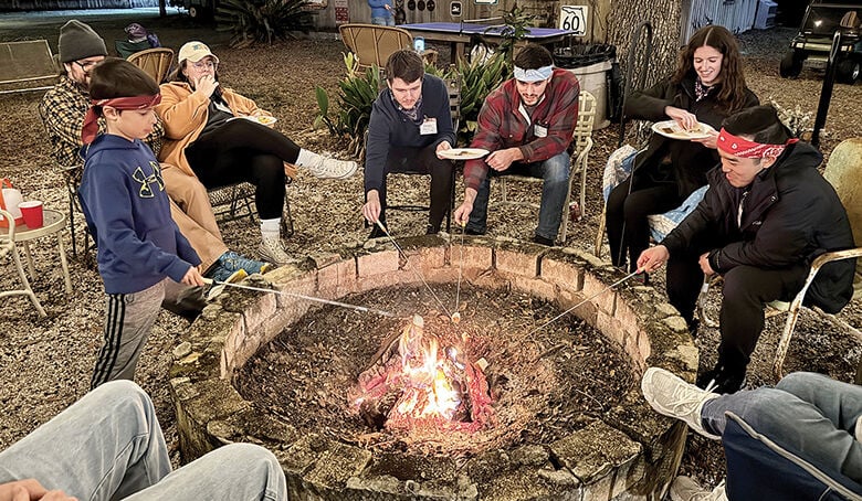 Members of the Marlow and Litzell families, as well as friends of the happy couple, make s’mores during the Camp Marlow weekend festivities.