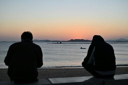 Men sit by the sea during sunset on Pingtan island on December 29, 2025