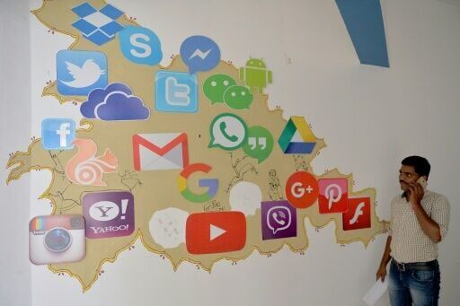 A man passes by a mural depicting various social media apps in Bangalore on March 22, 2018