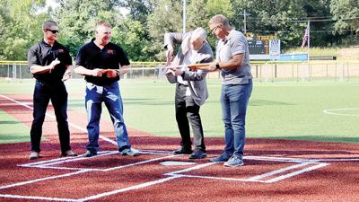 Festus R-6 Superintendent Link Luttrell cuts the ribbon during a ceremony to open the new Tiger Field on campus at Festus High School