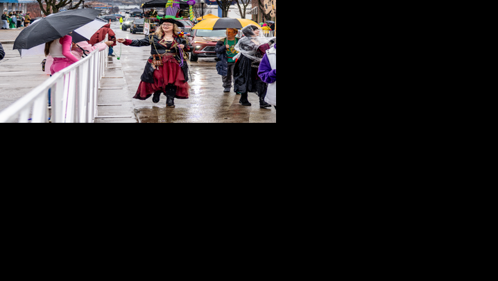 A pirate hands out beads as the Mardi Gras Parade travels down the street in the rain.