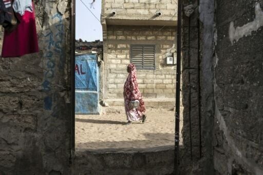 A woman walks on a street in Mbour, a coastal city which like other Senegalese fishing areas has had multiple residents migrate