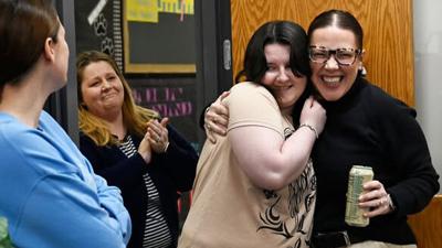 Alyiah Gusoskey and Tiffany Bungenstock, a counselor at Senn-Thomas Middle School, share a hug as school staff and faculty gather to celebrate Gusoskey completing her cancer treatment.