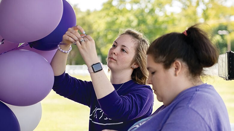 Hannah Jones attaches cards with memories of her mother, Amanda Jones, to helium-filled balloons.
