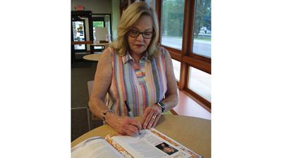 Sen. Elaine Gannon signs a page of “You Can, Too!” at De Soto Public Library.