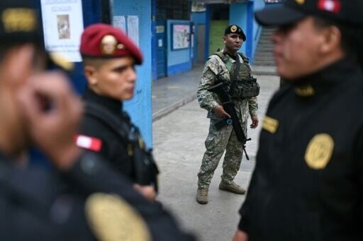 A member of the Armed Forces and police officers stand guard at a school before its reopening as a polling station in Lima on April 13, 2026, after logistical failures prevented tens of thousands of people from voting in presidential and legislative ele...