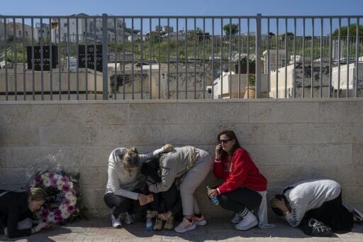 People take cover as a war siren blasts during the funeral of Sarah and Ronit Elimelech, who were killed the previous day in an Iranian missile attack, in Bet Shemesh on March 2, 2026