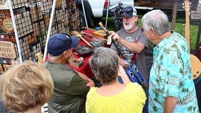 From left, Kim Mooney, Mike Mooney, Emma Welsch and Bob Welsch listen as Joe Sears, center, shows off a one-string cigar box guitar.