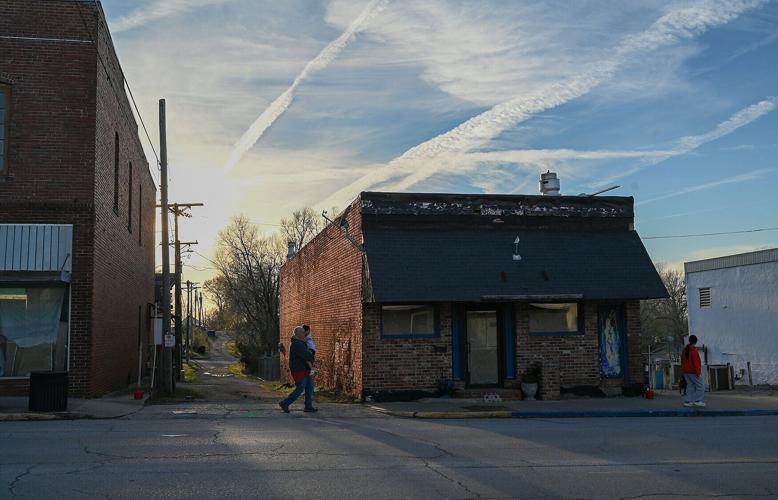 Aircraft contrails are left in the sky as people walk through town