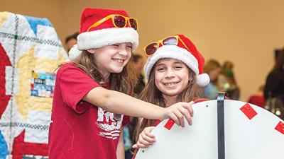Friends Harper Perschbacher of Imperial and Charlotte Caputa of Arnold spin the wheel at the Smoothie King booth at last year’s Arnold Kiwanis Club Giving and Light Fair.