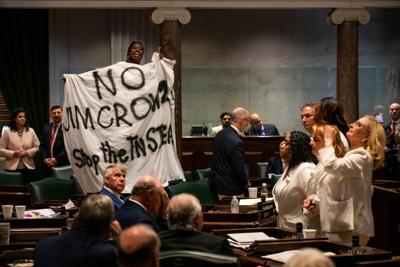 Sen. Charlane Oliver (D-Nashville) stands on her desk and displays a banner in protest of congressional redistricting, May 7, 2026