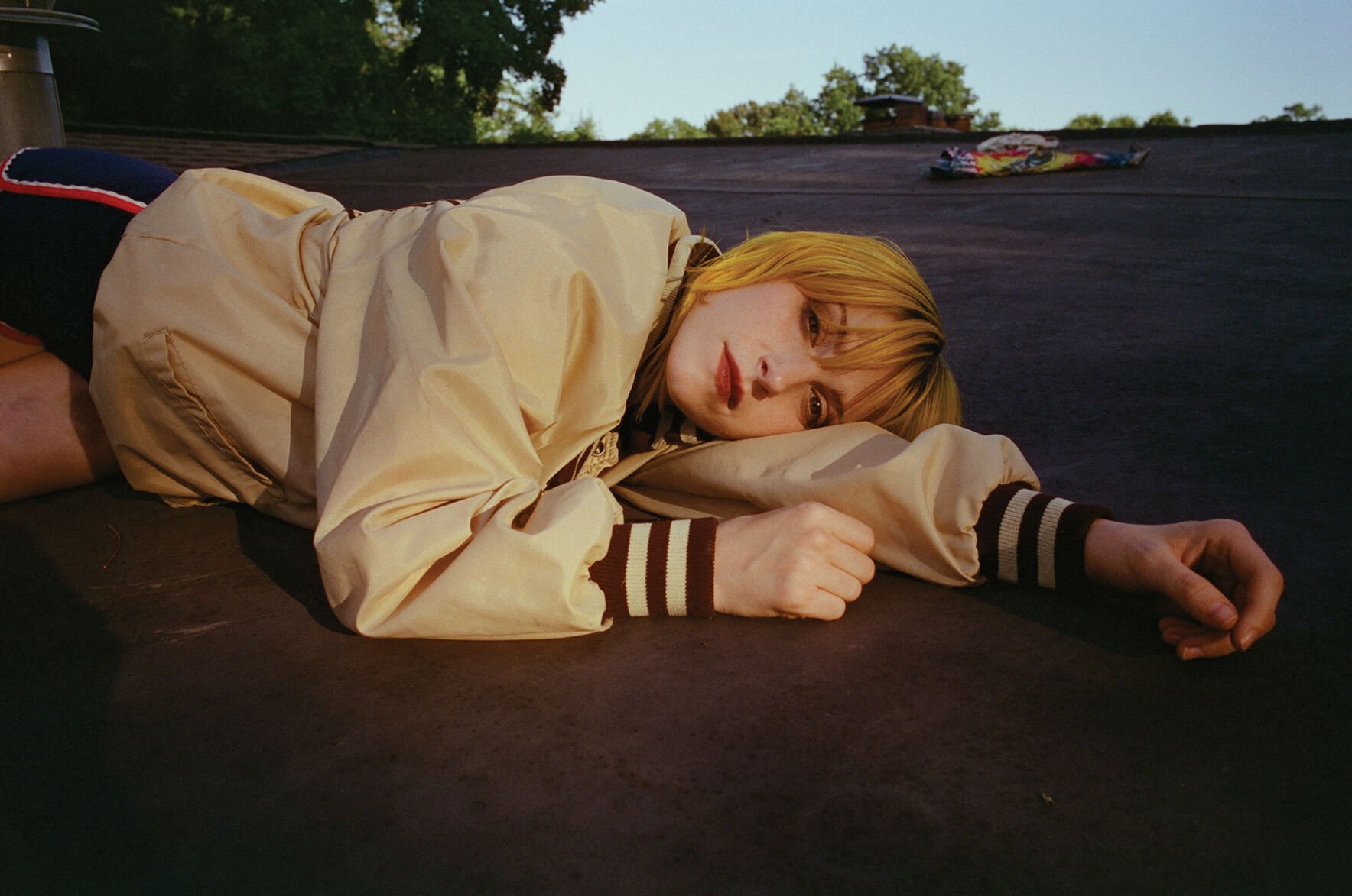 Hayley Williams press pic 2025 artist lies on the roof of a house wearing a cream warmup jacket