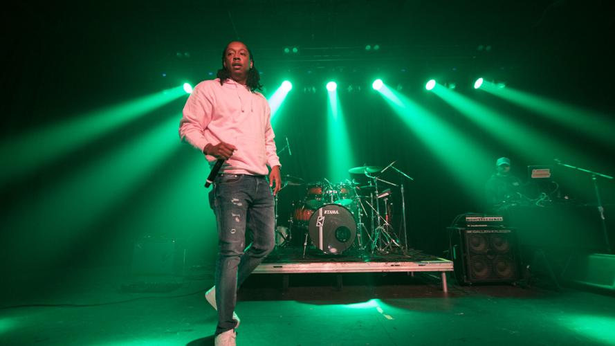 Starlito performs at Eastside Bowl artist stands onstage in a pink hoodie backlit with green lights