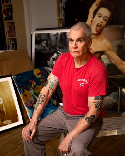 Henry Rollins wearing a red shirt, seated in front of his collection at home in Nashville, October 2026